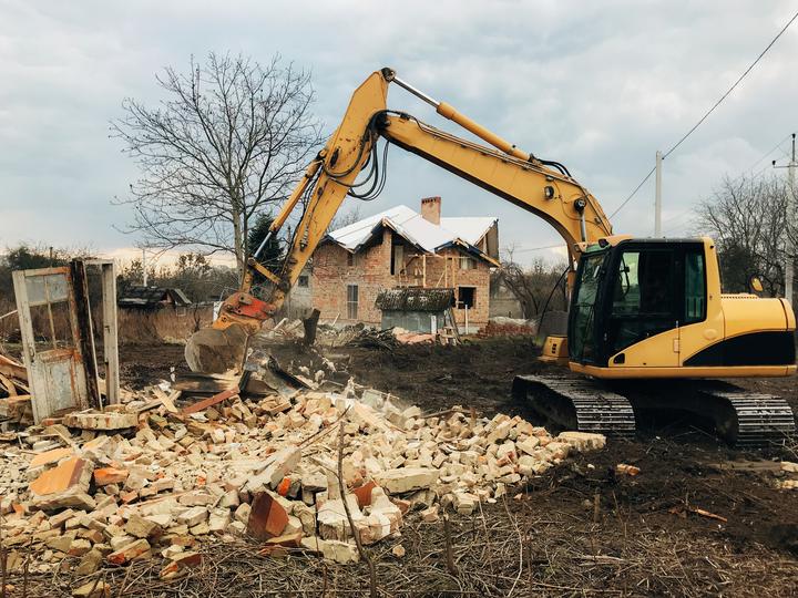 House being demolished by an excavator