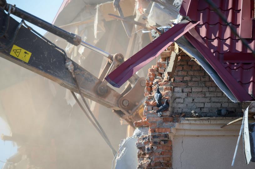 House being demolished by an excavator