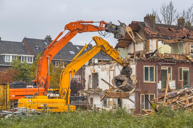 House being demolished by an excavator